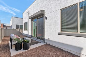 A white house with a patio and a chair.at Marketside Villas at Verrado, Buckeye, 85396